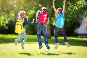 Drei Schüler von hinten, die vor Freude hoch springen