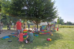 Kinder auf einer Wiese mit großen bunten Bausteinen